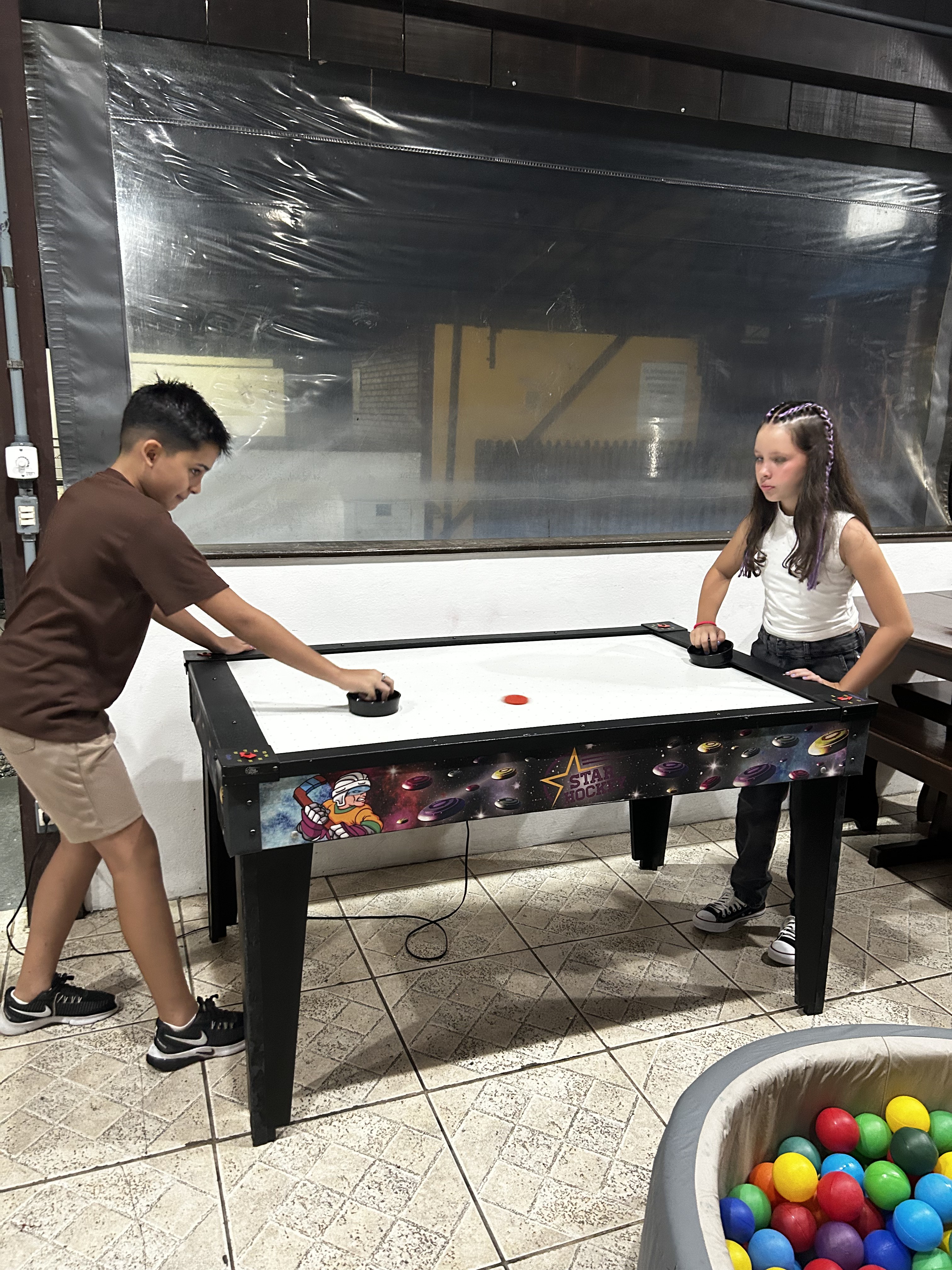 Monitores para eventos em Joinville acompanhando crianças em mesa de air hockey